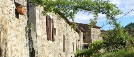 A narrow stone street flanked by traditional stone buildings with arched doorways and wooden shutters.