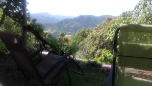 A chair and a table in a shaded outdoor area with a view of a valley and mountains. - Typical Cevennes house for people with mountain view (Mialet)