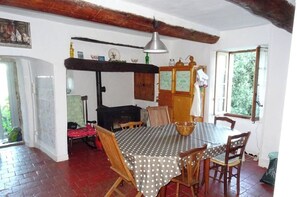 Enjoy meals in this cozy dining area with a large round table, wooden chairs, and a brick floor.