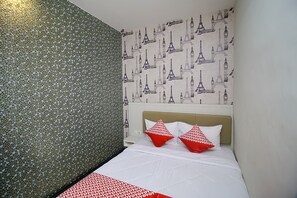 Experience the charm of Paris in this stylish room, featuring a comfortable bed with a white bedspread and two decorative pillows, and a unique Eiffel Tower wall design.