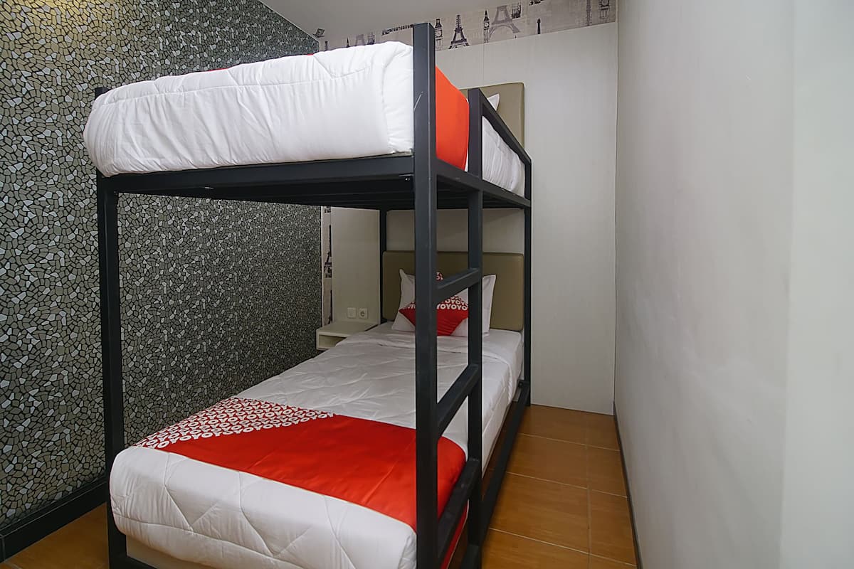 A bunk bed with white and red bedding, a small bedside table, and a wall with a mosaic pattern.