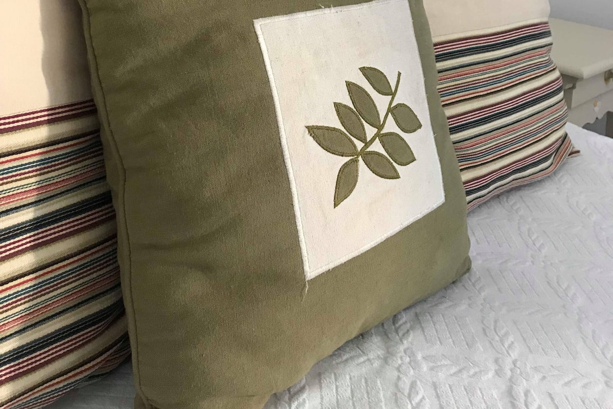 A bed with a white headboard, multiple pillows, and a green pillow with a leaf design.