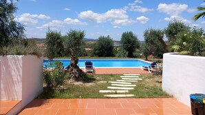 Una piscina con un cielo azul despejado y nubes al fondo.