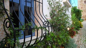 Un edificio con un ventanal azul y barandilla de balconada de hierro forjado.