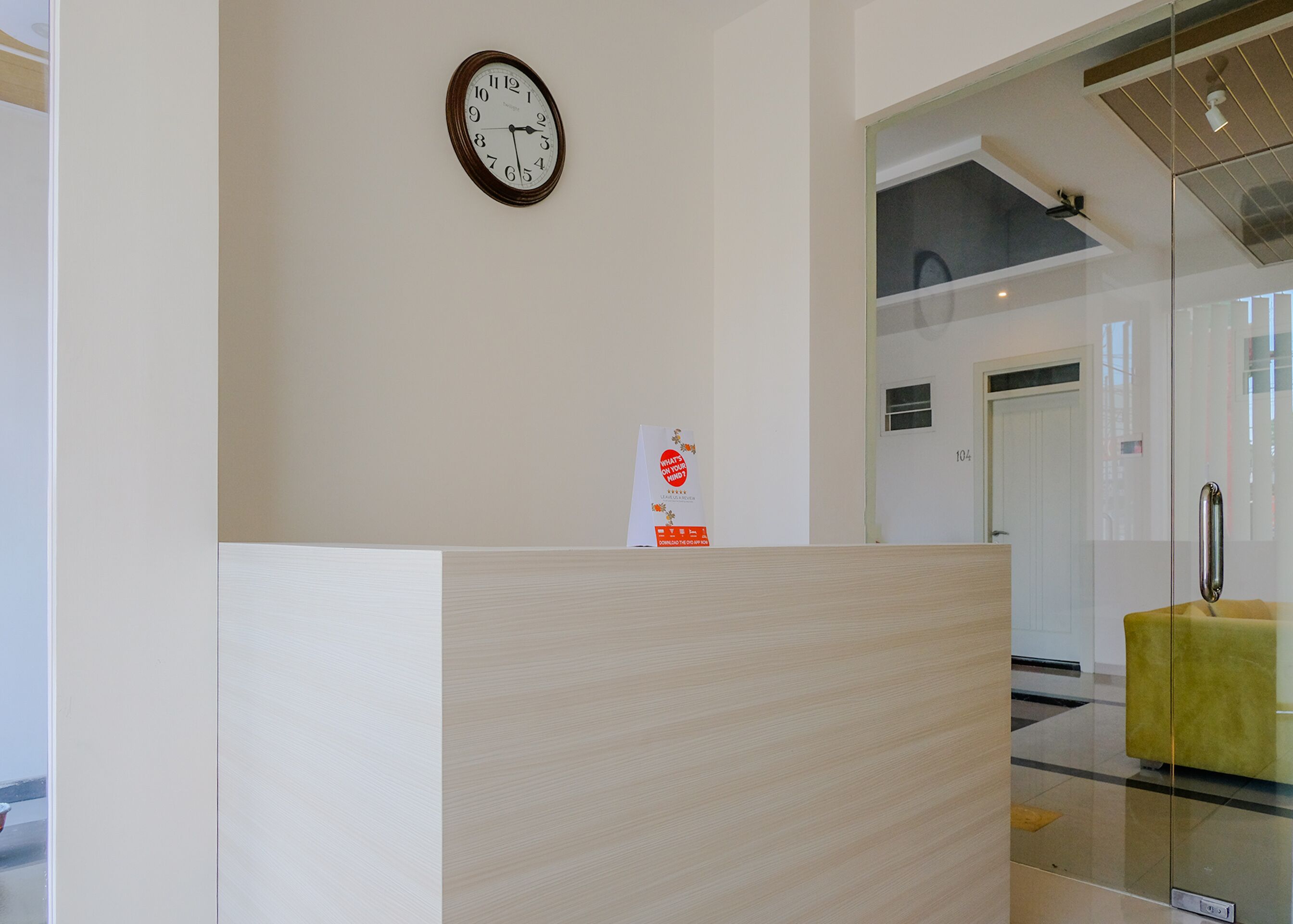 Un área de recepción con un mostrador de madera, un reloj en la pared y un cartel en la pared.