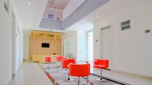 Um interior moderno com piso xadrez, cadeiras vermelho vivo e um alto teto com varanda.