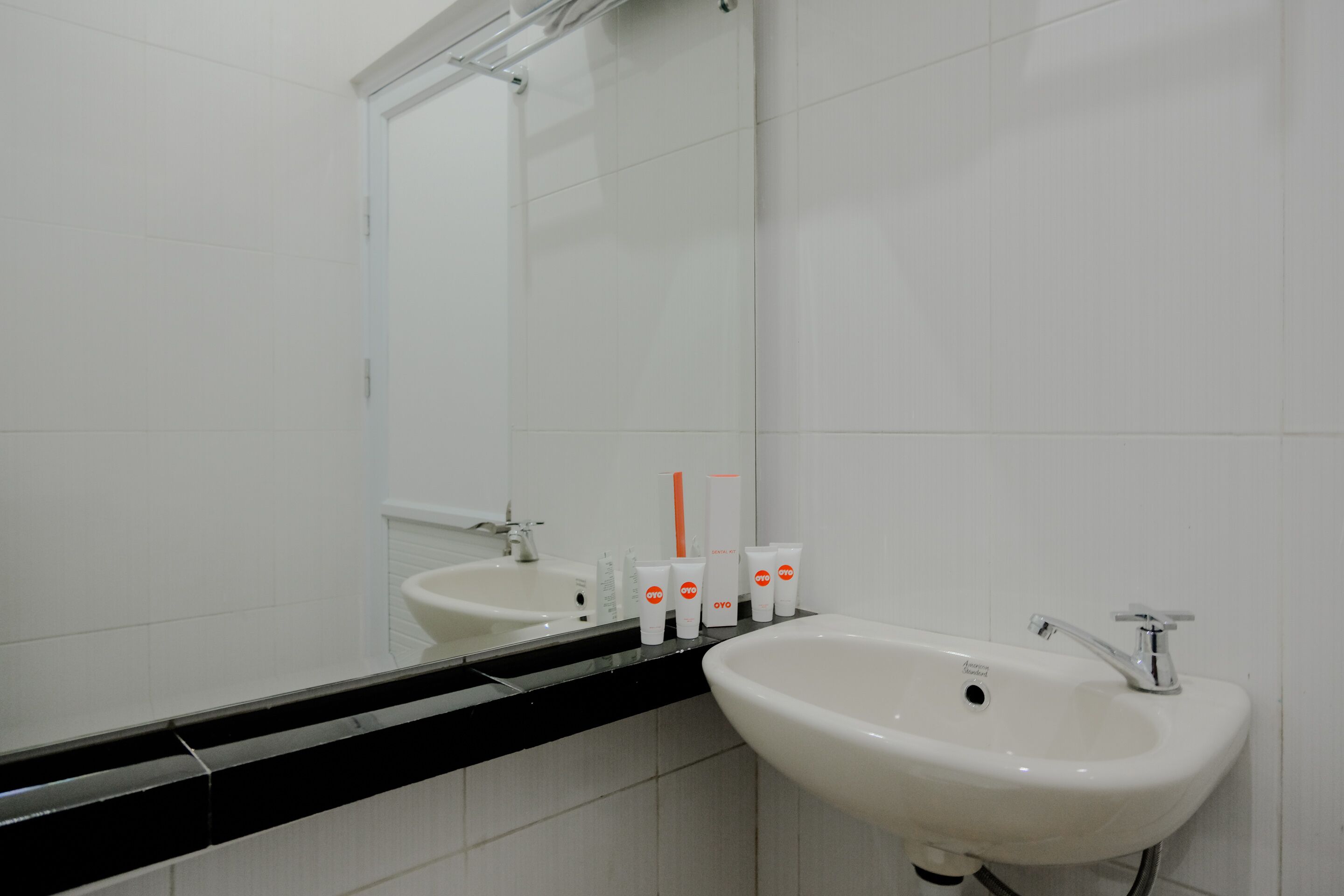Un baño con un lavamanos blanco, un espejo y artículos de aseo en la encimera.
