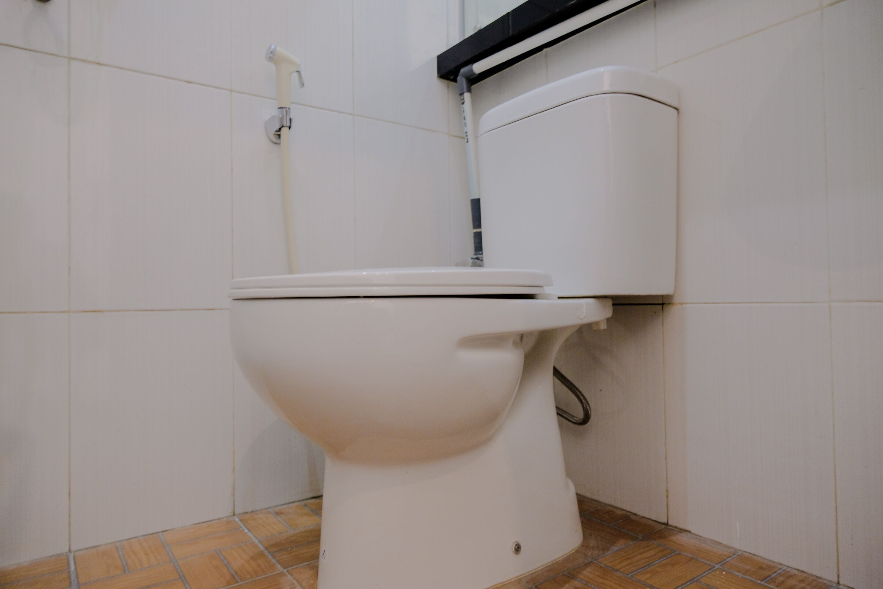 Un vàter blanc en un bany amb parets i terra emblaquenats.