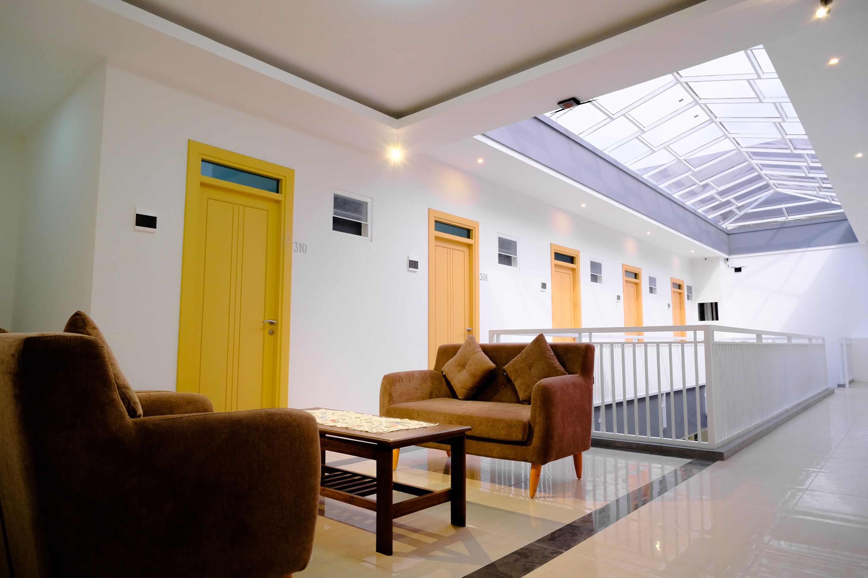 Un moderno vestíbulo de hotel con techo alto, tragaluces y una zona de estar con una mesa.