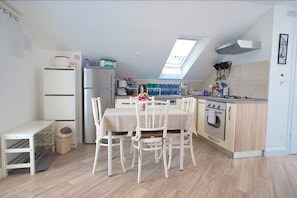 A compact kitchen with a dining table, chairs, a refrigerator, a stove, and a skylight. - Villa Marghareta 1 - Apartment Margaretha (Dubrovnik)