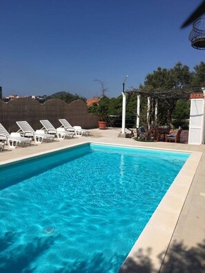 A rectangular swimming pool with clear blue water, surrounded by white lounge chairs and a pergola. - Villa Marghareta 1 - Apartment Margaretha (Dubrovnik)