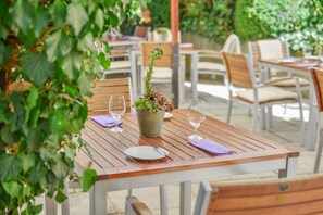 An outdoor dining area with wooden tables and chairs, a potted plant centerpiece, and a glass of water on each table. - Mayers Waldhorn Hotel (Kusterdingen)