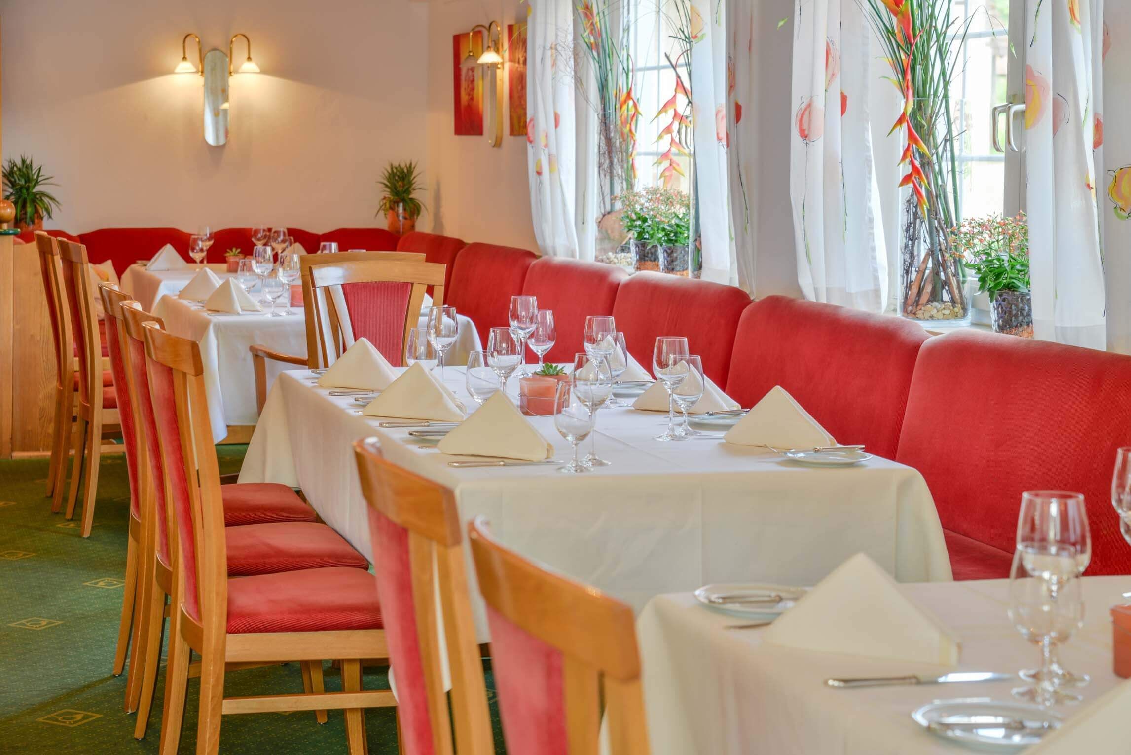 Un restaurante con asientos tapizados en rojo y manteles blancos.