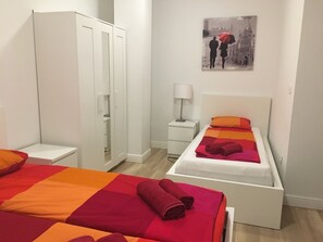 A bedroom with two beds, a wardrobe, a bedside table with a lamp, and a painting on the wall. - Villa Marghareta - Deluxe App Marghareta (Dubrovnik)