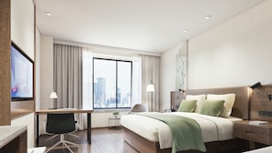 A modern hotel room with a large bed, a desk, and a view of a cityscape. - GreenTree Inn Ningbo Beilun District Meishan Beach Business Hotel (Ningbo)