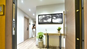 A hallway with a wooden floor, a reception desk with a plant, and a framed picture on the wall. - Feel Athens Studios at Monastiraki (Athens)