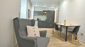 A modern living room with a grey sofa, a dining table with two chairs, and a kitchen in the background. - Feel Athens Studios at Monastiraki (Athens)