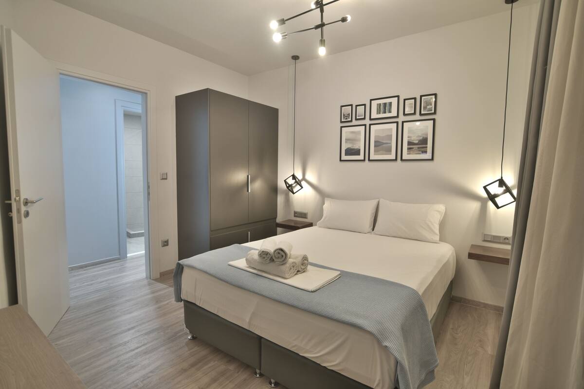 A modern bedroom with a large bed, a wardrobe, bedside tables, and framed pictures on the wall.