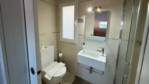 A compact bathroom with a toilet, sink, and shower. - Palacete de la Constitución ÁTICO (Málaga)