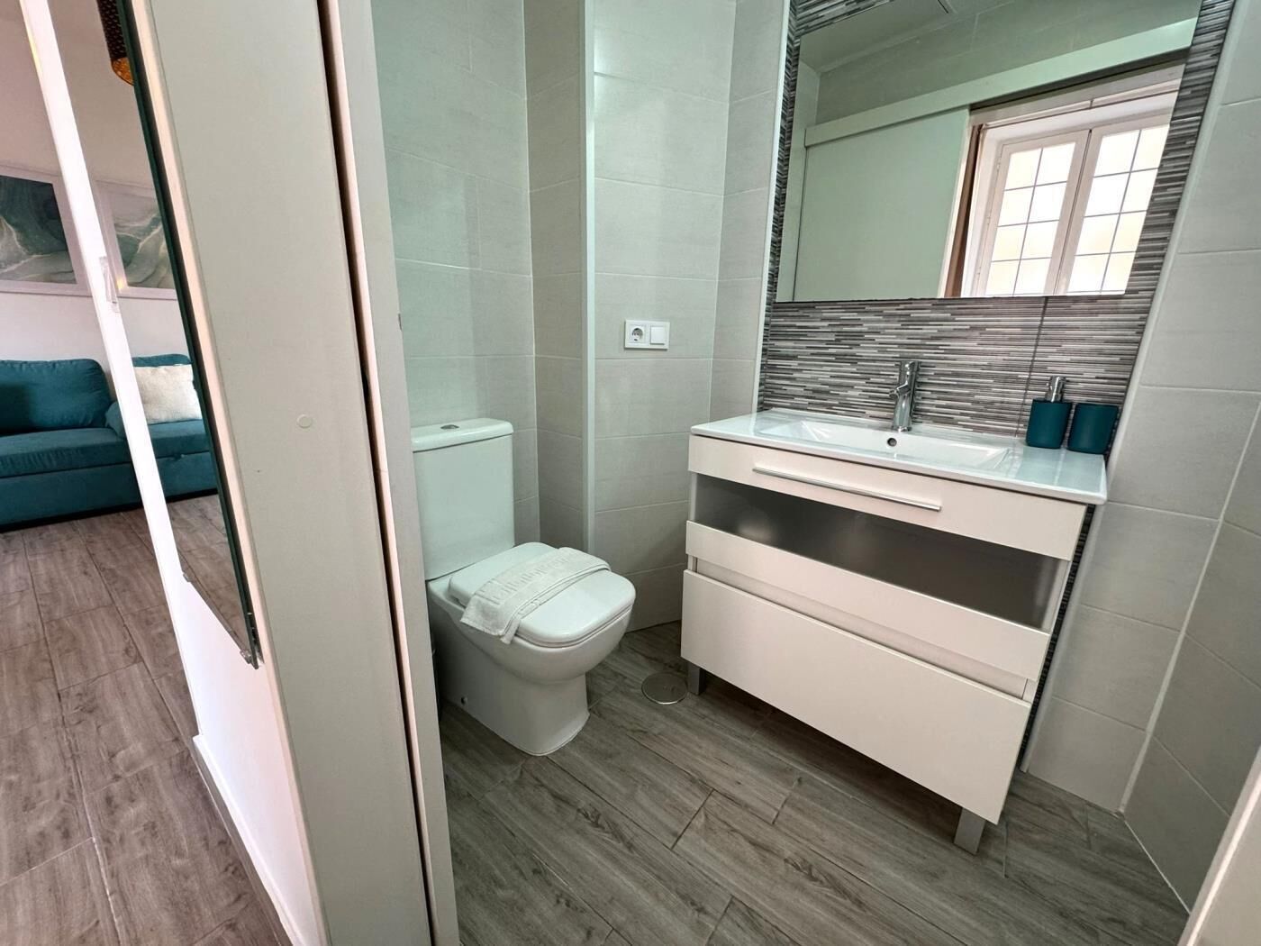 A modern bathroom with a toilet, sink, and mirror.