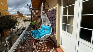 A balcony with a hanging chair, a view of the street, and a building in the background. - Studio with terrace next to the Atarazanas Market by Málaga Planners (Málaga)