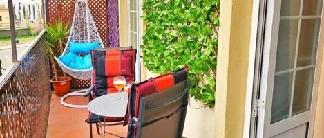 A balcony with a chair, a small table, and a potted plant.