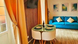A dining area with a round table, chairs, and a bottle of wine. There is a blue sofa in the background. - Studio with terrace next to the Atarazanas Market by Málaga Planners (Málaga)