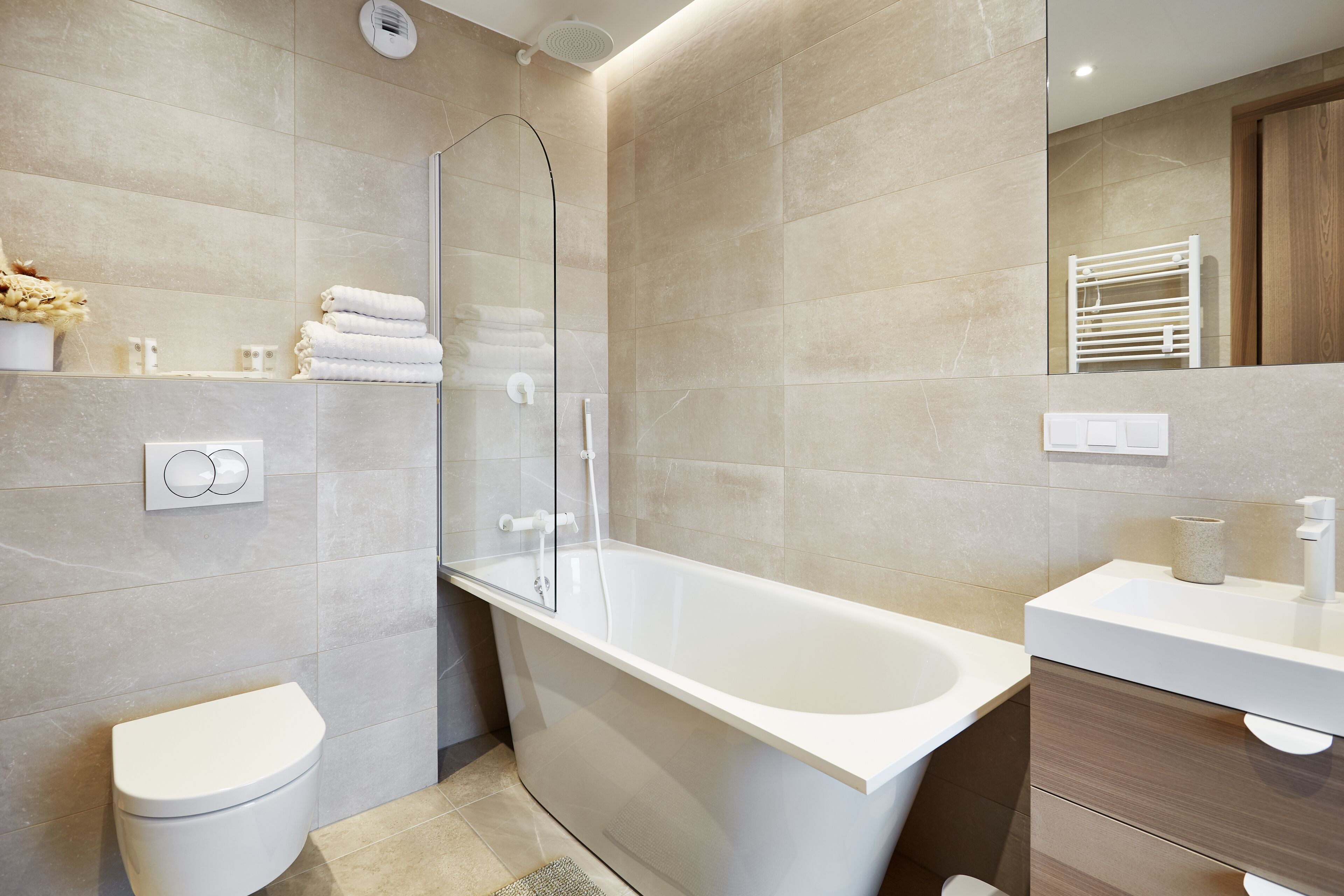 A modern bathroom with a bathtub, toilet, and a vanity with a mirror.