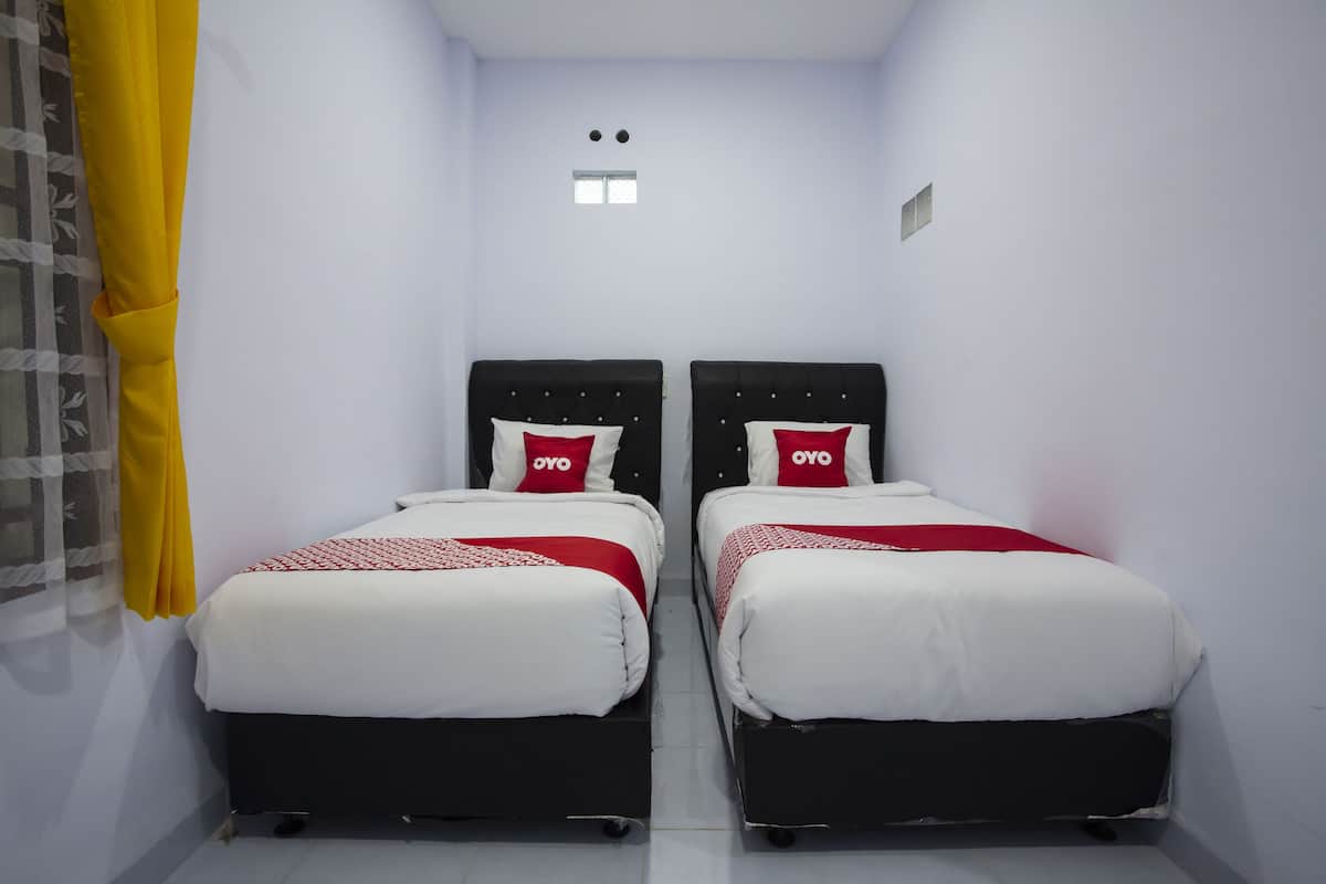 A small, clean room with two beds, each with a black headboard and white bedding.