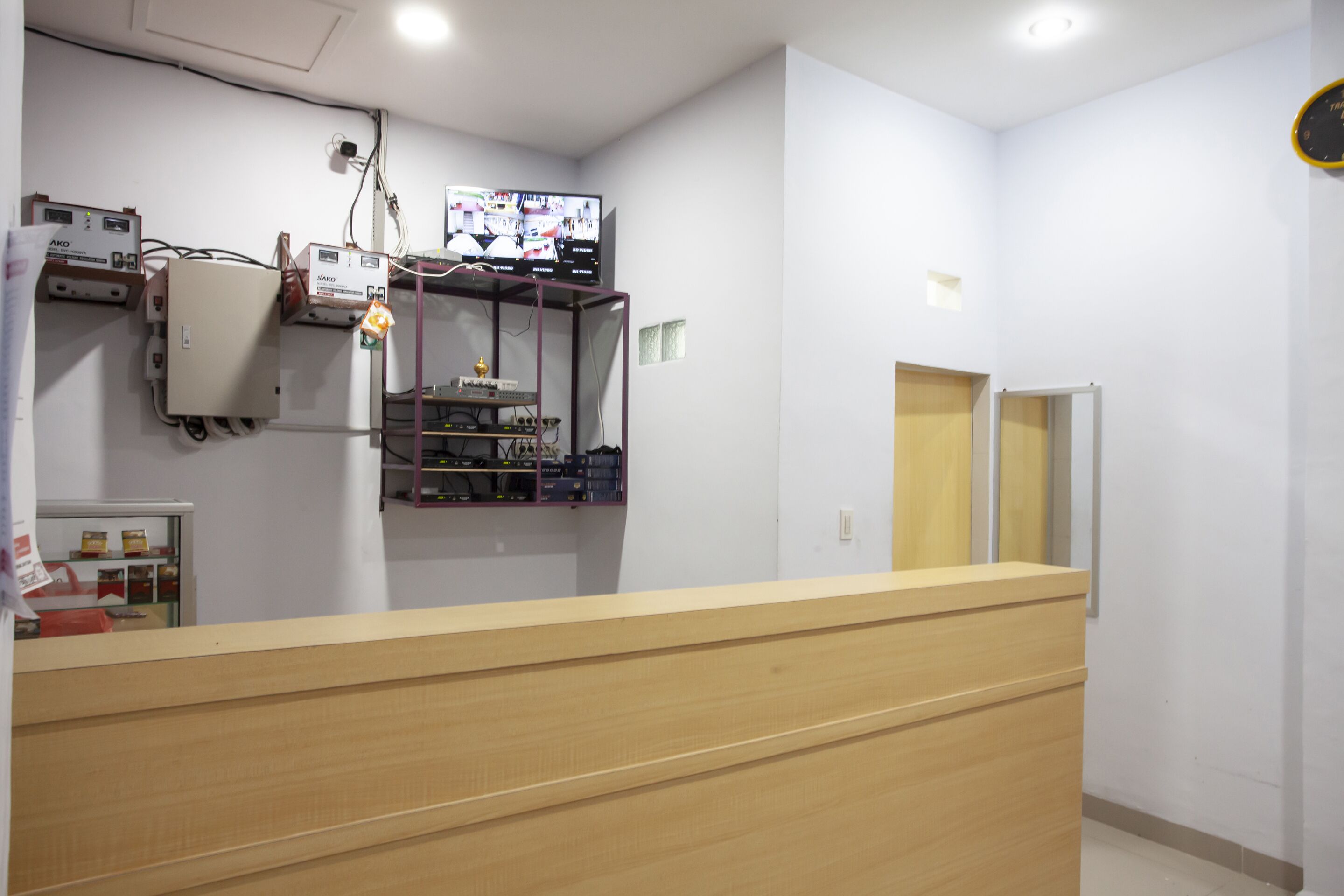 Aula, jossa on puinen vastaanottotiski, seinälle asennettu televisio ja erilaisia elektronisia laitteita.