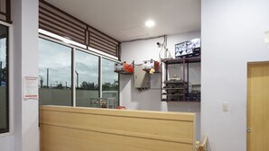 A room with a wooden bench, a window with blinds, a shelf with electronic equipment, and a door. - Hotel O Sopou Penginapan Rinal & Tuah (Bahapal Raya)
