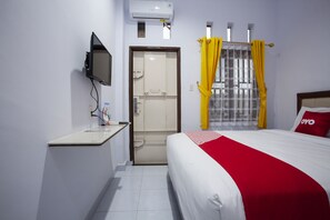 A hotel room with a bed, a TV mounted on the wall, a small table with a bottle, and a door leading to a bathroom. - Hotel O Sopou Penginapan Rinal & Tuah (Bahapal Raya)