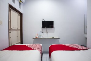 A hotel room with two beds, a TV mounted on the wall, and a small desk with a computer and some items. - Hotel O Sopou Penginapan Rinal & Tuah (Bahapal Raya)