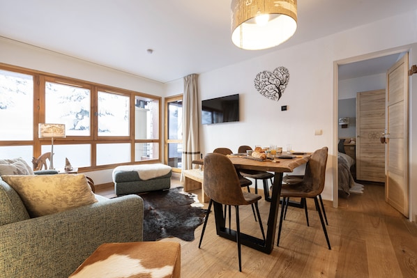 Relax in this inviting space with a sofa, dining table, and flat-screen TV, offering a serene view of the surrounding landscape.