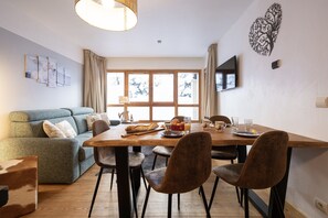 Relax in this inviting space with a dining table for four, a comfortable sofa, and a large window.