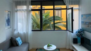 Una sala de estar con un ventanal grande, un sofá, una mesa de centro y un televisor.