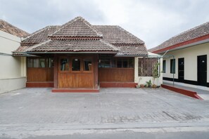 A traditional house with a tiled roof, wooden doors, and a paved courtyard. - OYO 1700 Danurejan Guesthouse (Yogyakarta)
