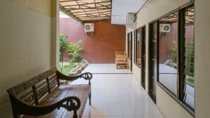 Un pasillo con un banco de madera, suelo de baldosas y vistas al exterior a través de amplias ventanas.