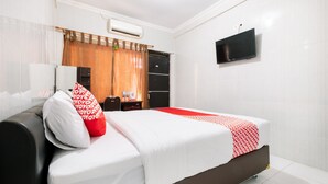 Una habitación de hotel con una cama, un televisor montado en la pared y un equipo de aire acondicionado.