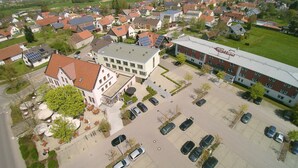 Un hotel con estacionamiento, rodeado de edificios residenciales y campos verdes.