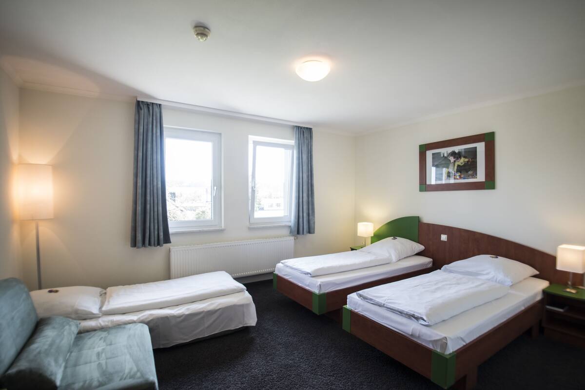 A hotel room with two single beds, a sofa, and a small table.