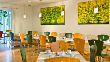 A dining area with multiple tables and chairs, featuring a modern design with a mix of colors.