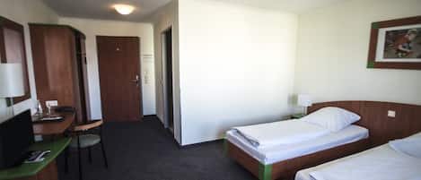 Habitación de hotel con dos camas individuales, un escritorio con silla, televisor y armario.