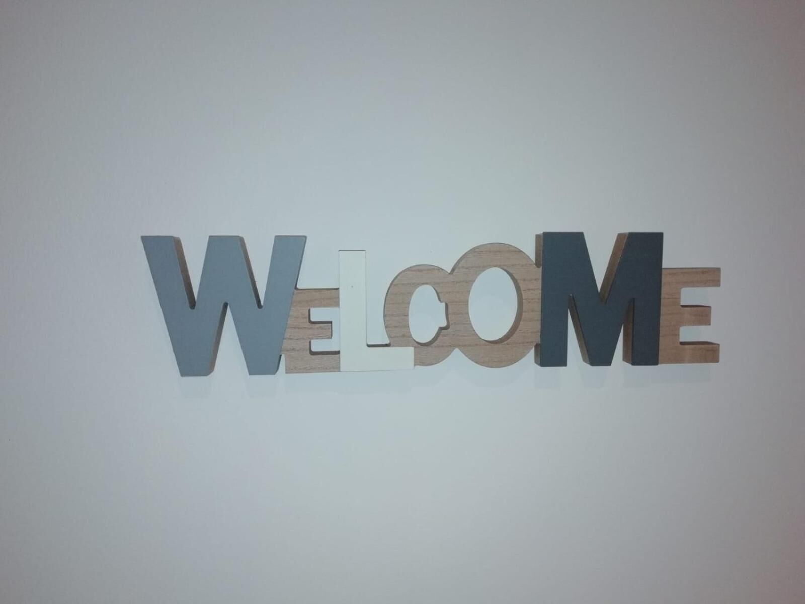 Un letrero montado en la pared con la palabra 'WELCOME' en letras grandes y tridimensionales.