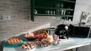 A kitchen counter with various food items, a coffee maker, and a microwave. - Good Morning Shopping (Serravalle Scrivia)