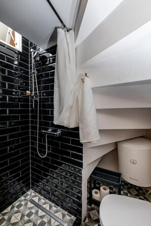 A bathroom with black tiled walls, a shower with a handheld showerhead, a toilet, and a sink with a black countertop. - Private Accomodation Linda (Dubrovnik)