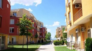 Una calle residencial con edificios de varios pisos, cielo despejado y una senda.