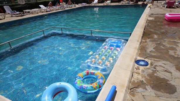 Una piscina con sillas de descanso y flotadores.