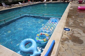 Une piscine avec des chaises longues et des bouées gonflables.