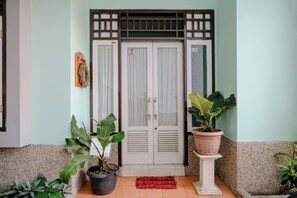 A building entrance with a double door, potted plants, and a red mat. - Hotel O Villa Hardi (Batu)